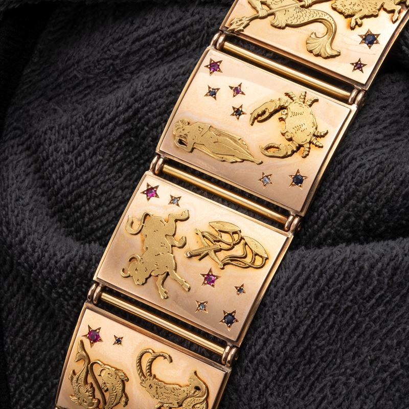 BRACCIALE IN ORO 18 KT RAFFIGURANTE I SEGNI DELLO ZODIACO ORNATO DA PICCOLI ZAFFIRI RUBINI E DIAM...